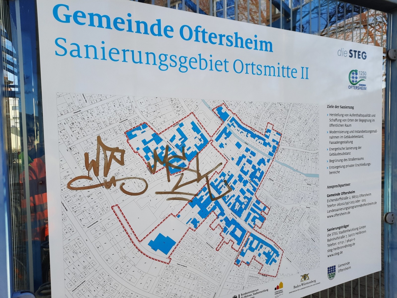 Hinweisschild zum Sanierungsgebiet Ortsmitte II mit Schmiererei versehen.