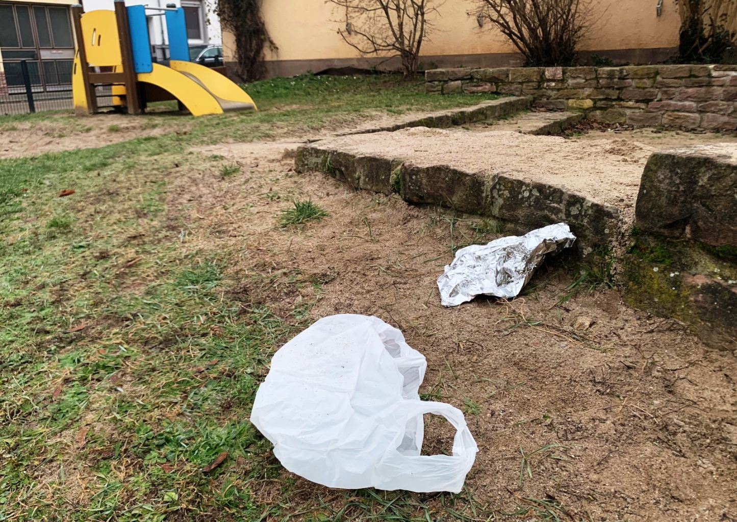 Verpackungsmüll ist auf dem Spielplatz verstreut.