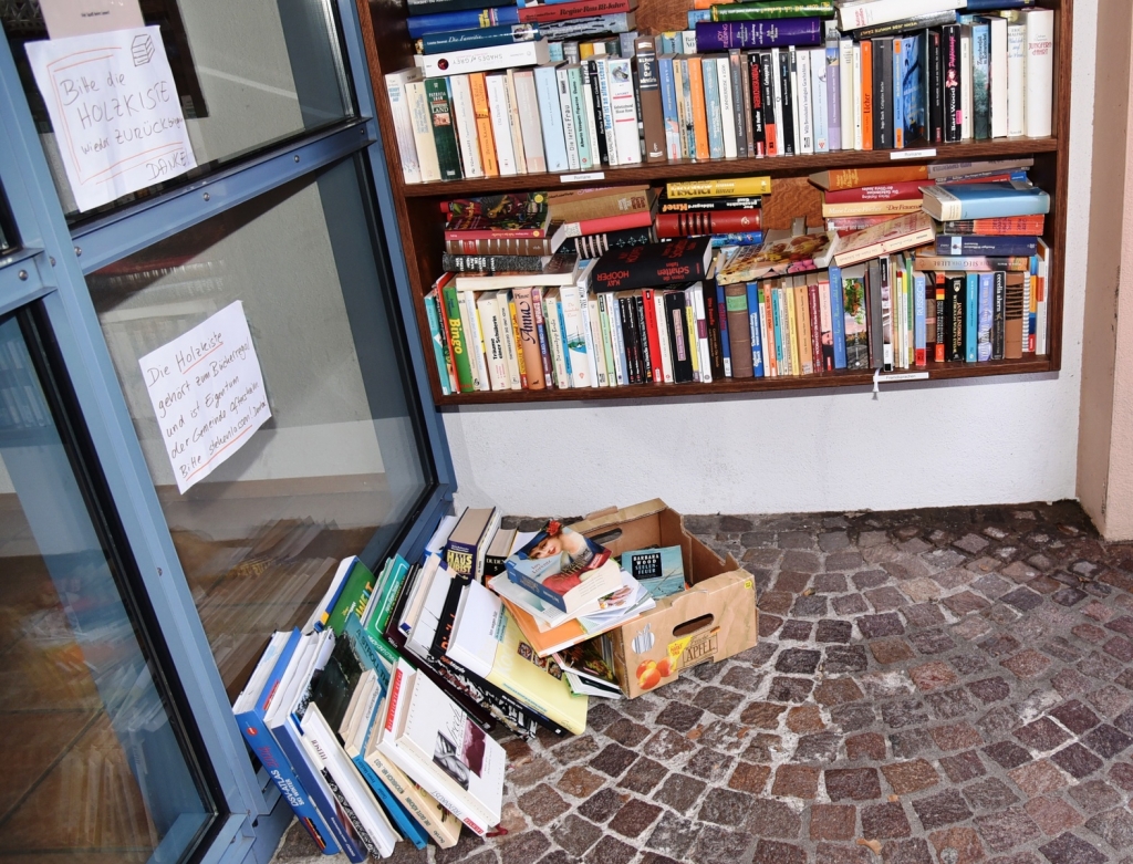 Weil die vermutlich gestohlene Bücherkiste immer noch fehlt, stehen die Bücher unterhalb des öffentlichen Bücherregals wieder auf dem Boden. Weil die vermutlich gestohlene Bücherkiste immer noch fehlt, stehen die Bücher unterhalb des öffentlichen Bücherregals wieder auf dem Boden.