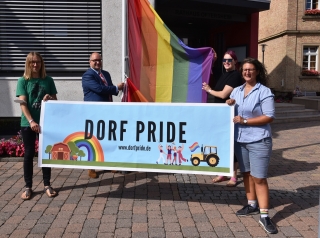 Die Regenbogenflagge wird wegen der Dorfpride-Demonstration am Rathaus gehisst. Von links nach rechts: Patrick Alberti, Bürgermeister Jens Geiß, Johannah Illgner, Sarah Kinzebach Die Regenbogenflagge wird wegen der Dorfpride-Demonstration am Rathaus gehisst. Von links nach rechts: Patrick Alberti, Bürgermeister Jens Geiß, Johannah Illgner, Sarah Kinzebach
