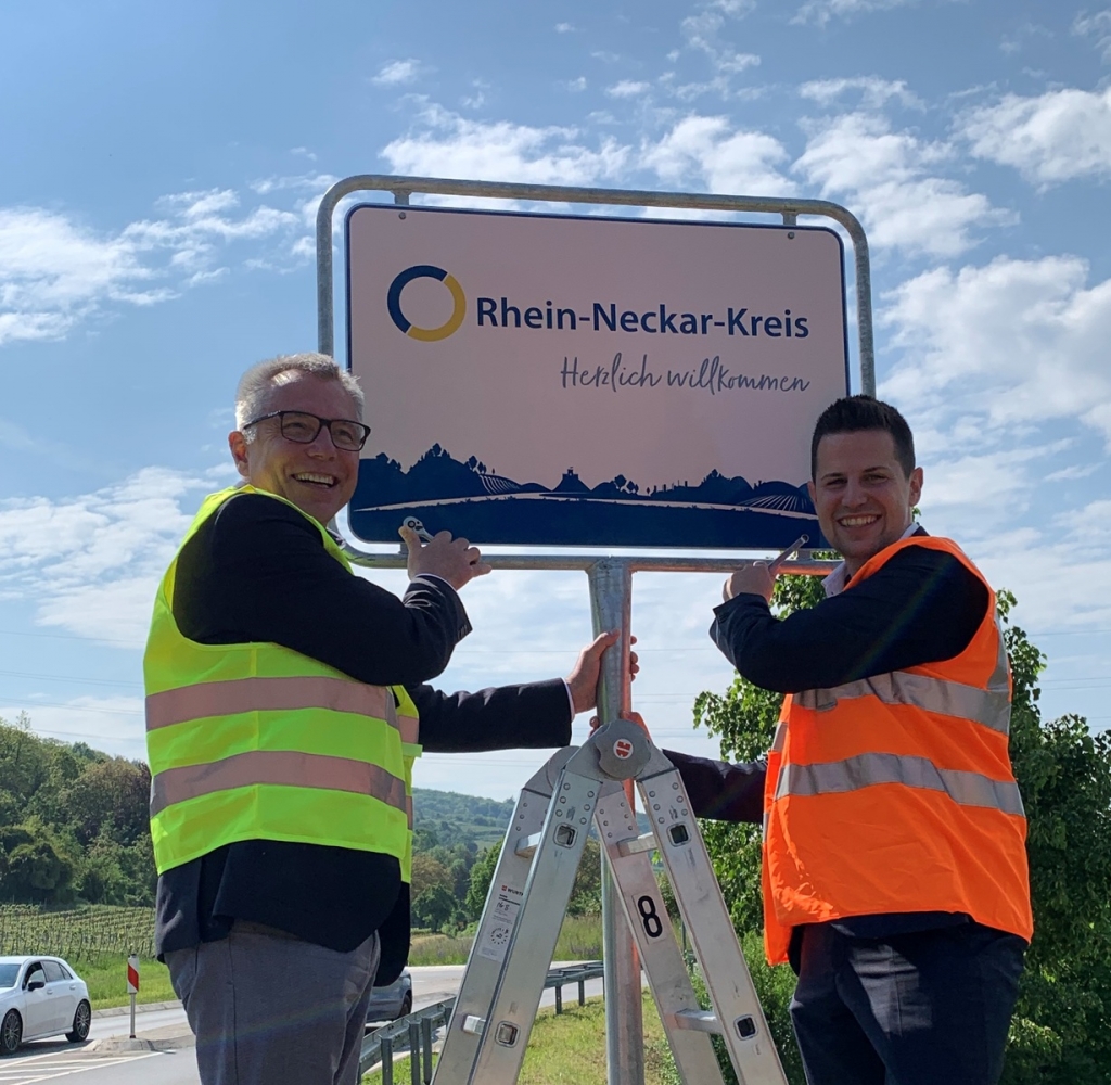 Landrat Stefan Dallinger und Bürgermeister Benjamin Köpfle freuen sich über das erste Willkommensschild im Landkreis. (Bild: Landratsamt Rhein-Neckar-Kreis) Landrat Stefan Dallinger und Bürgermeister Benjamin Köpfle freuen sich über das erste Willkommensschild im Landkreis. (Bild: Landratsamt Rhein-Neckar-Kreis)