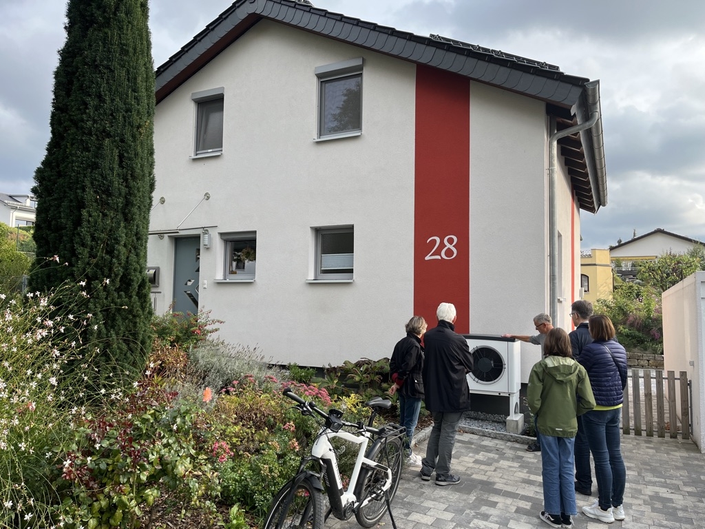 Menschen begutachten eine Wärmepumpe vor einem Wohnhaus. Bild: KliBA. Menschen begutachten eine Wärmepumpe vor einem Wohnhaus. Bild: KliBA.
