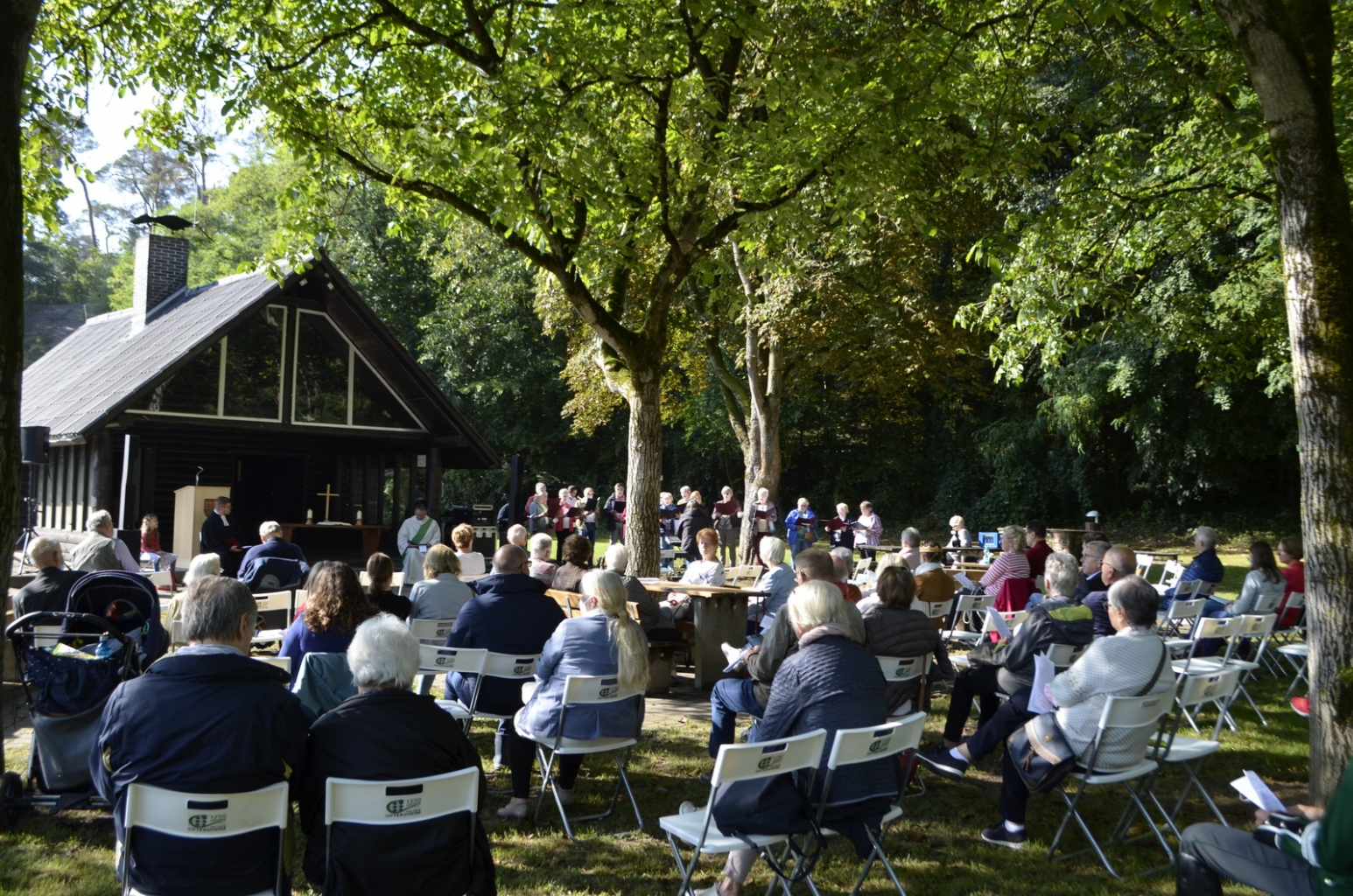 Besucher*innen vor der Grillhütte beim Gottesdienst zum Tag des Waldes.