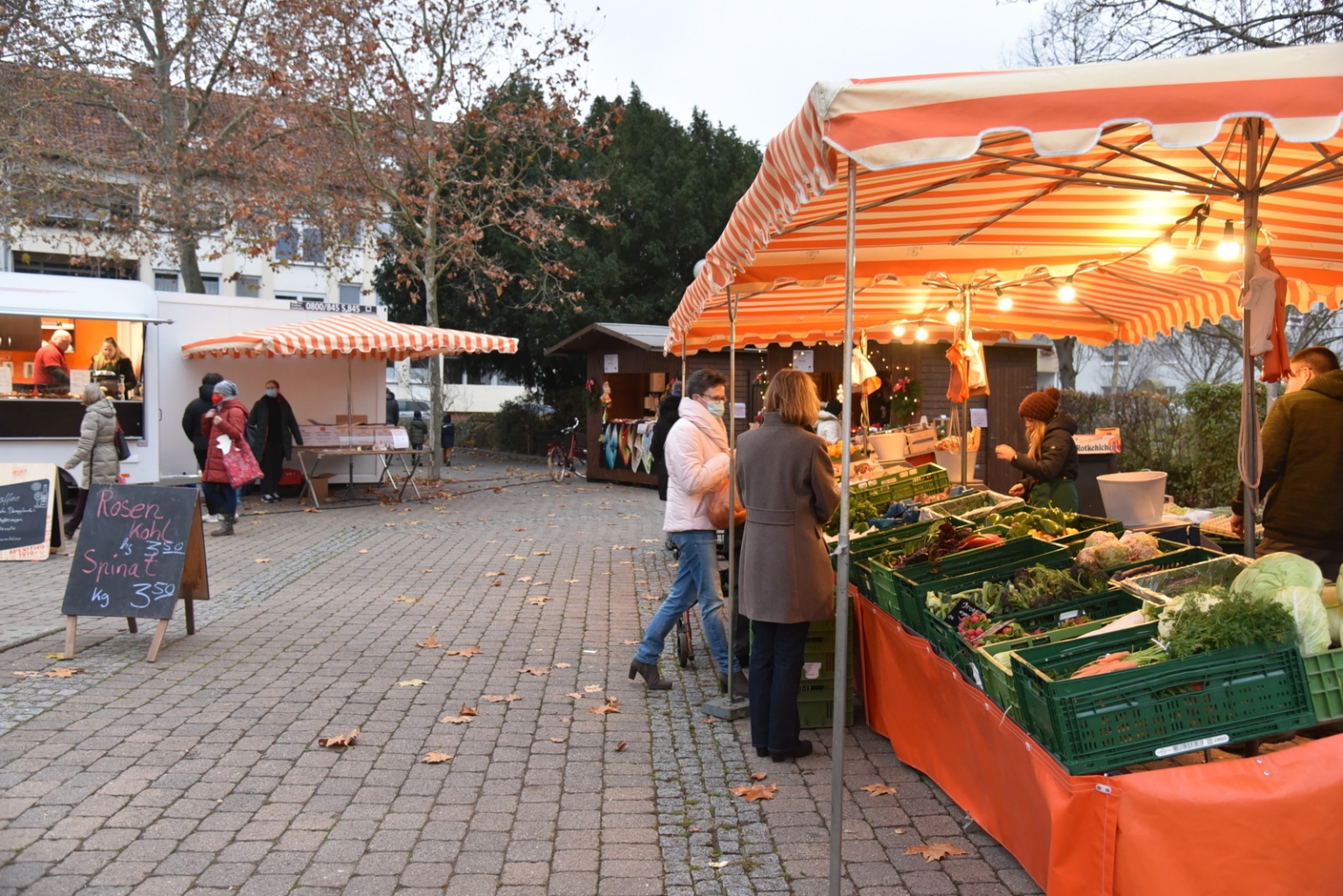 Blick über den Wochenmarkt, im Hintergrund die Weihnachtshütten.