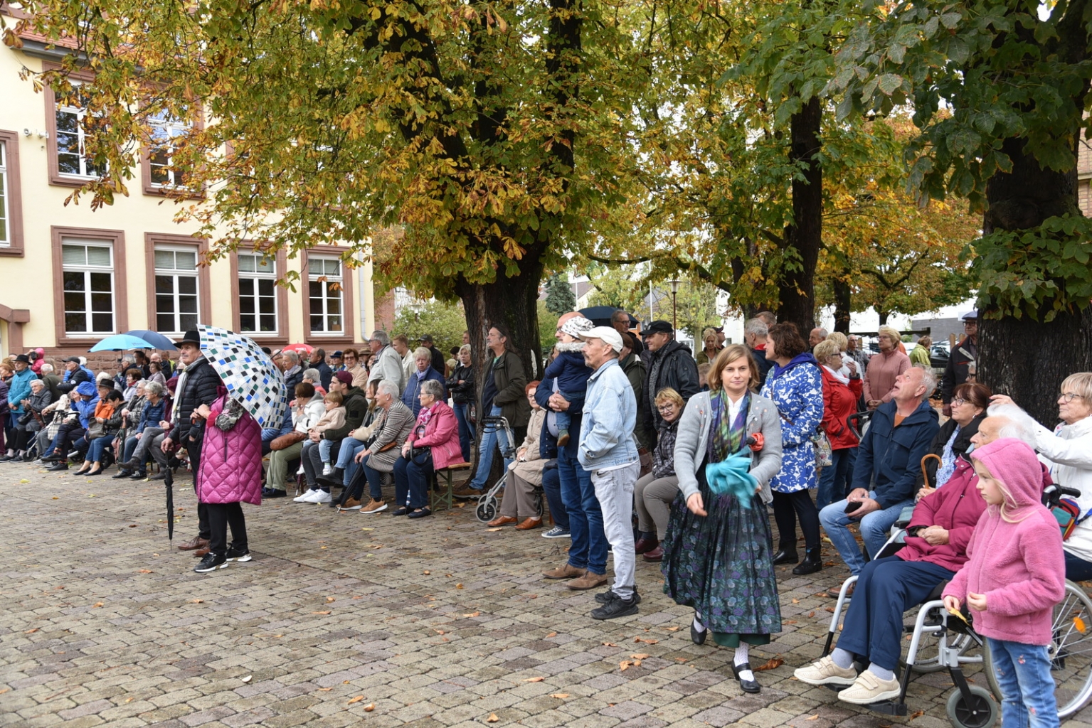 Besucher*innen auf dem Schulhof trotzen dem Regen.