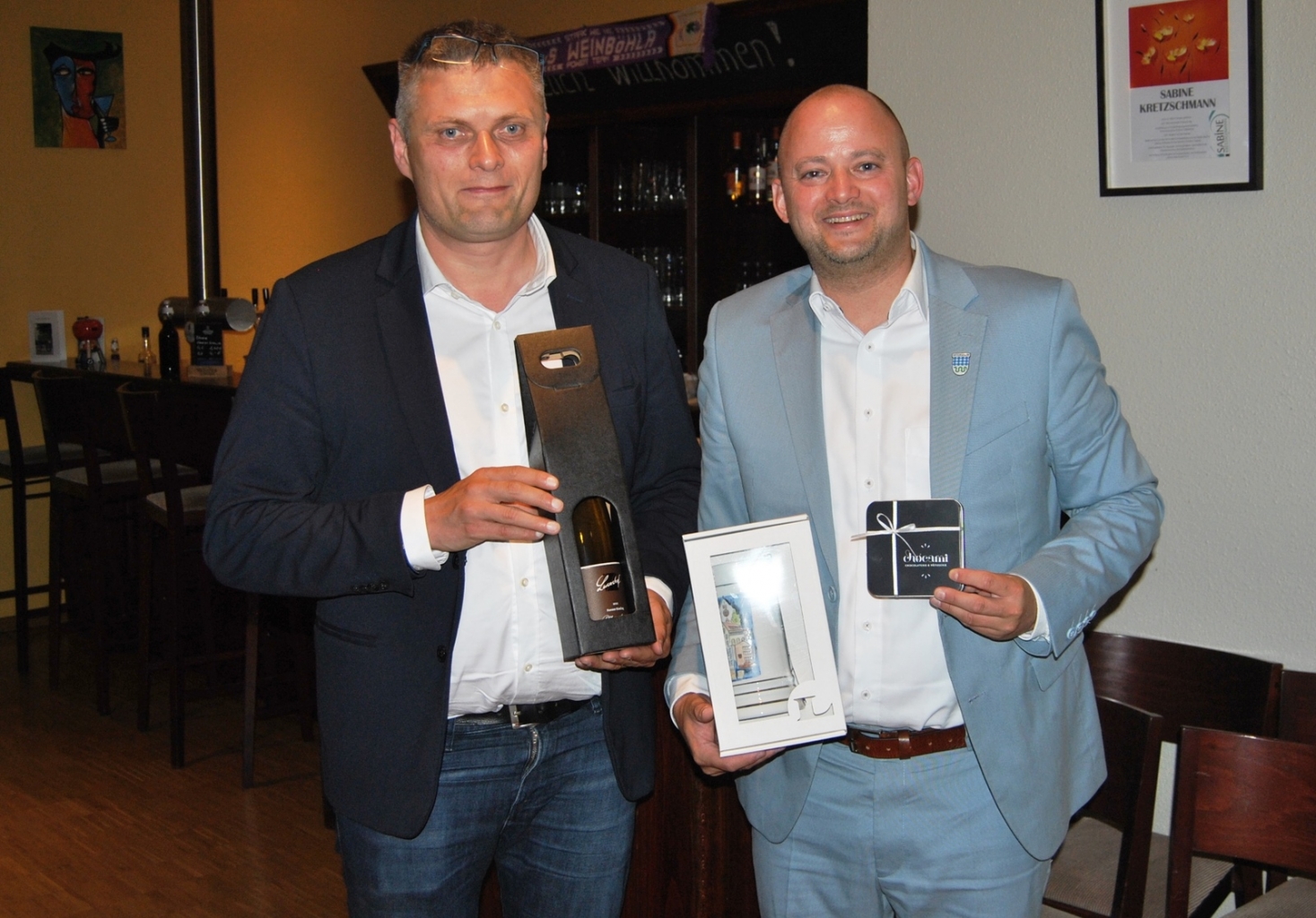 Bürgermeister Pascal Seidel übergibt Bürgermeister Siegfried Zenker in Weinböhla Geschenke.